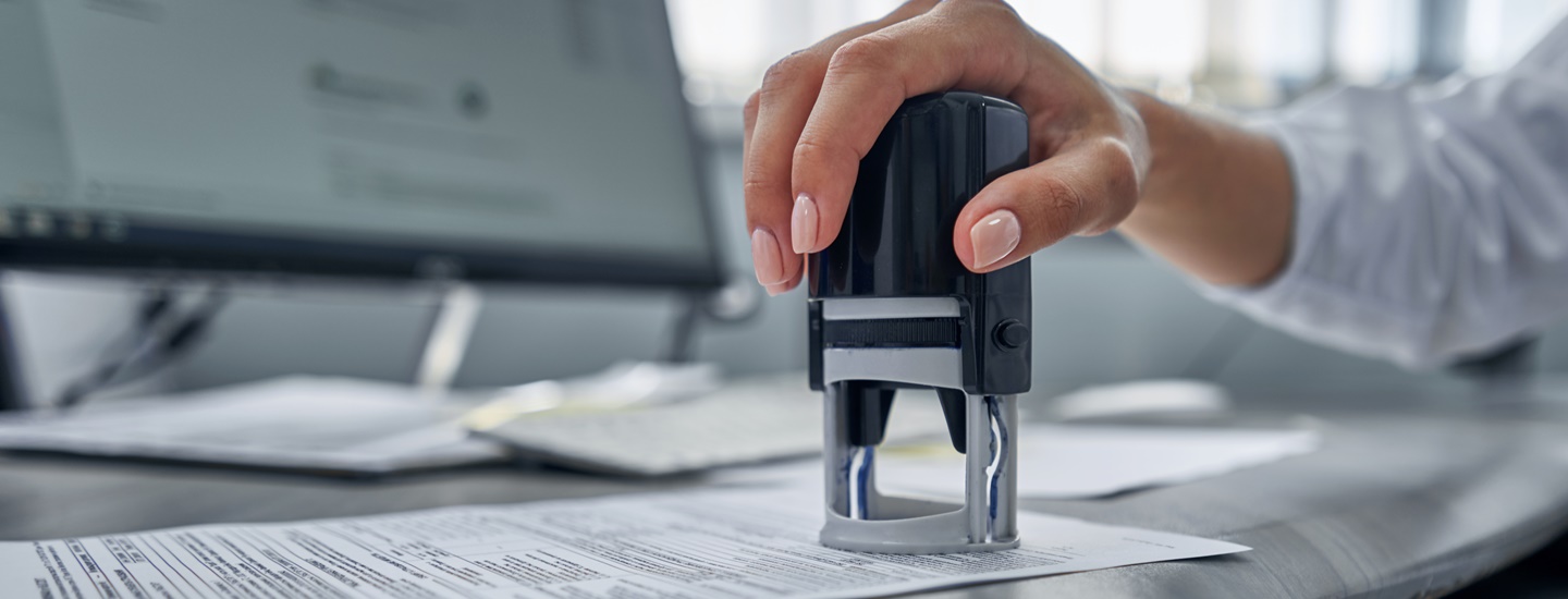 A woman holds a document stamp in her hand